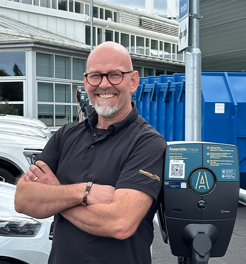 Rikard Grahn står med armarna i kors bredvid en laddbox från Assemblin Charge.